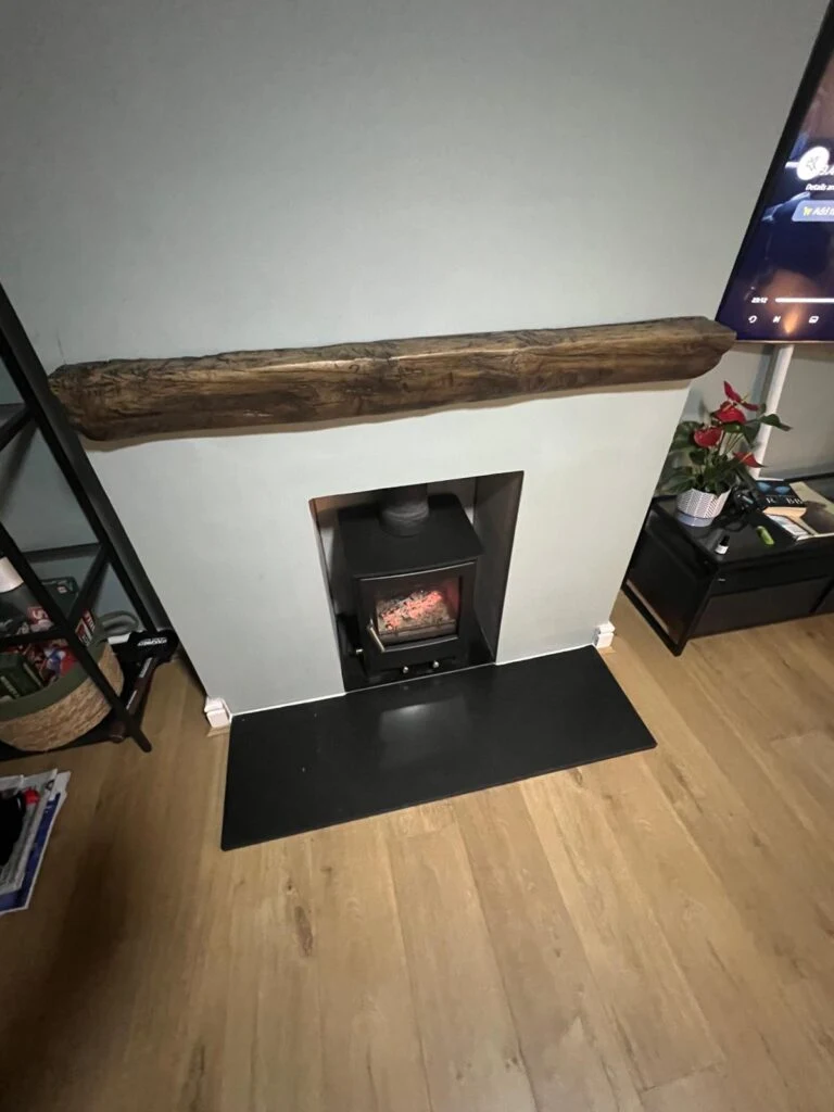 Recessed stove beneath a timber mantel and finished hearth