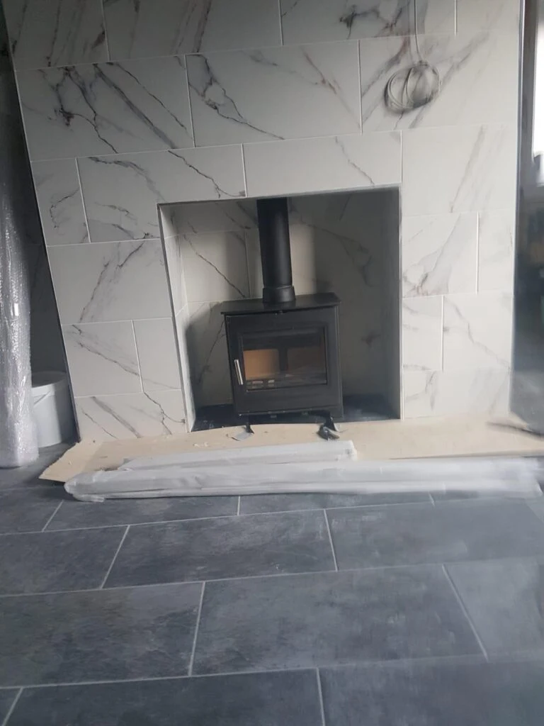 Stove fitted within a pale patterned fireplace surround
