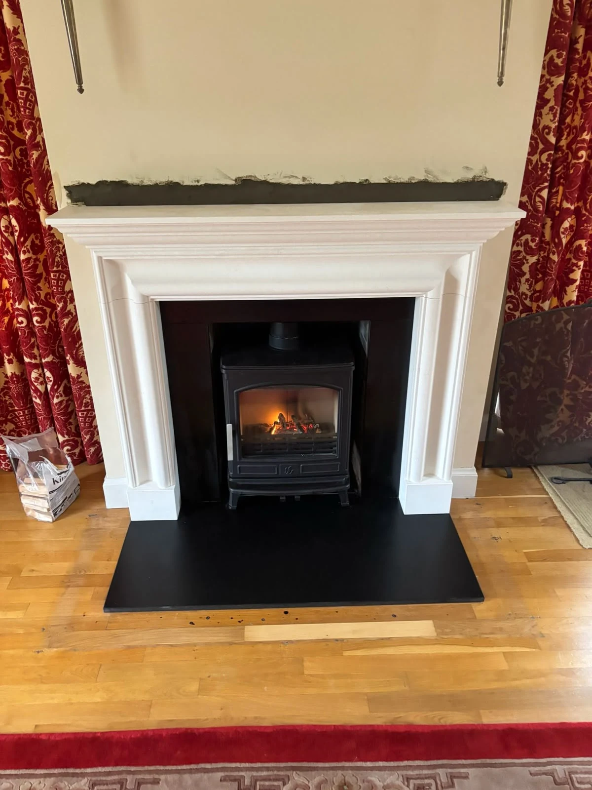 Lit stove in a white traditional fireplace with a black hearth