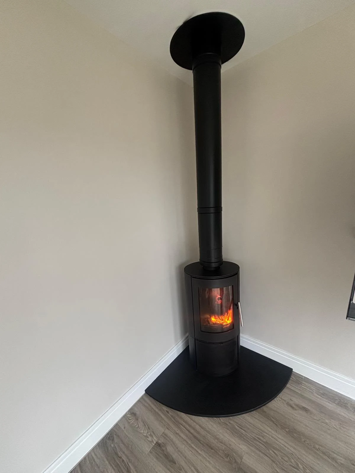 Finished corner stove installation with a curved hearth