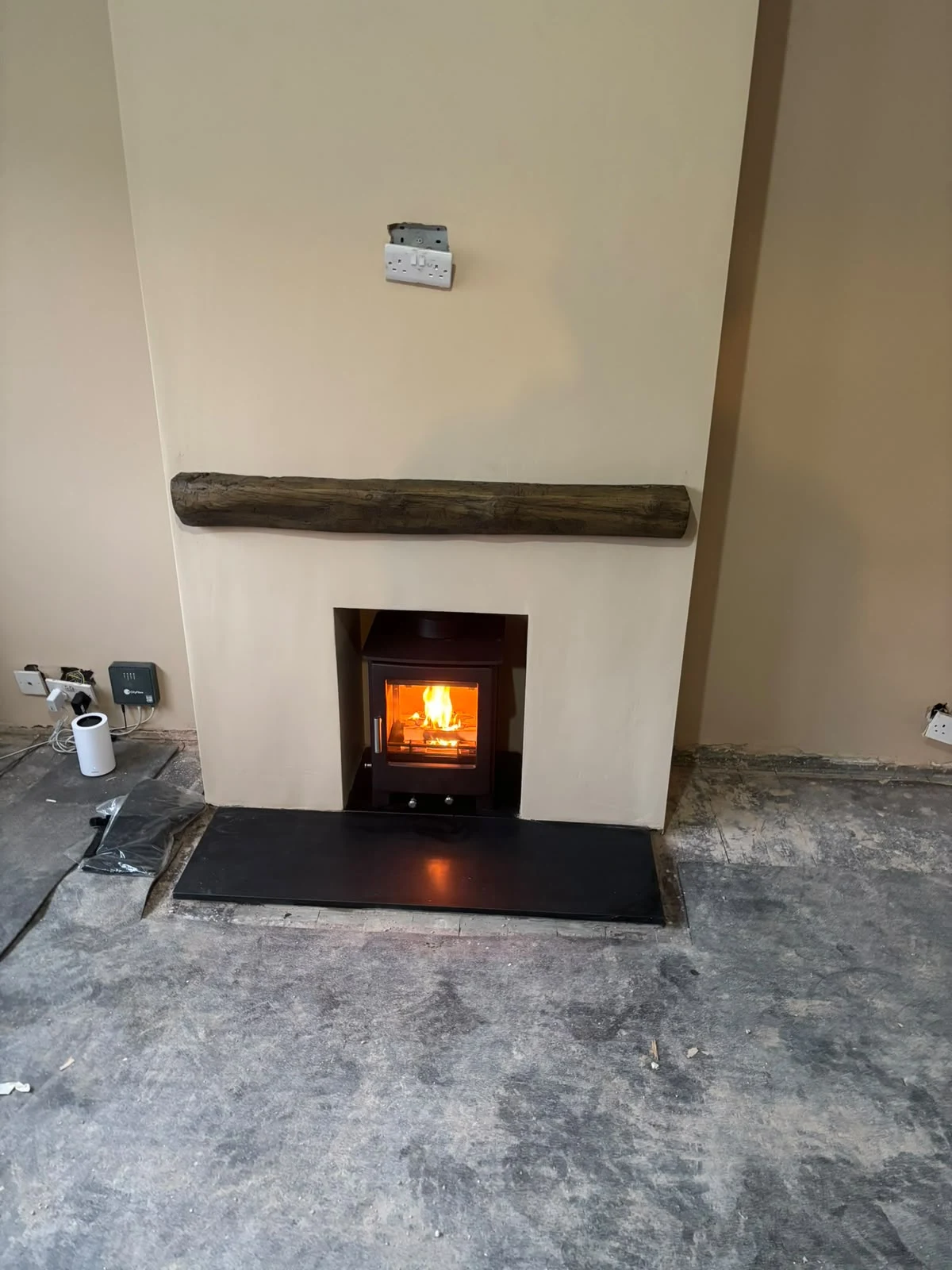 Lit recessed stove beneath a timber mantel